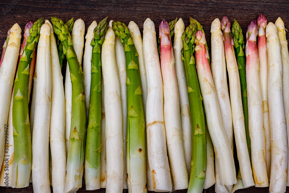 White and green fresh asparagus on the table, close up. Different varieties of German row green and white asparagus on the table.