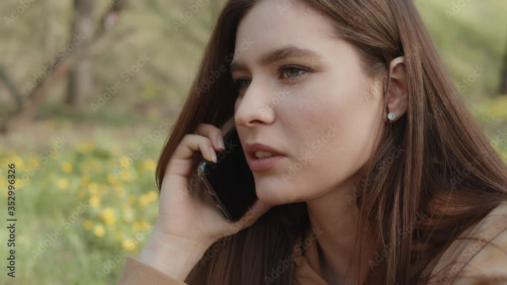 Teen girl talking on the phone outdoors, teenager in park, young woman student on grass Teen girl talking on the phone outdoors, teenager in park, young woman student on grass