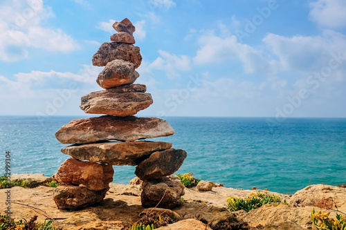 stone tower on a rock by the sea. sky with clouds, the concept of harmony, energy of life and meditation.
