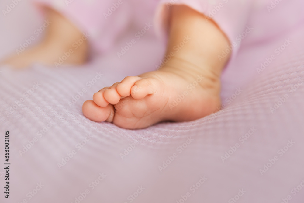 Baby girl foot on lilac background, tiny toes in a selective focus Baby girl foot on lilac background, tiny toes in a selective focus