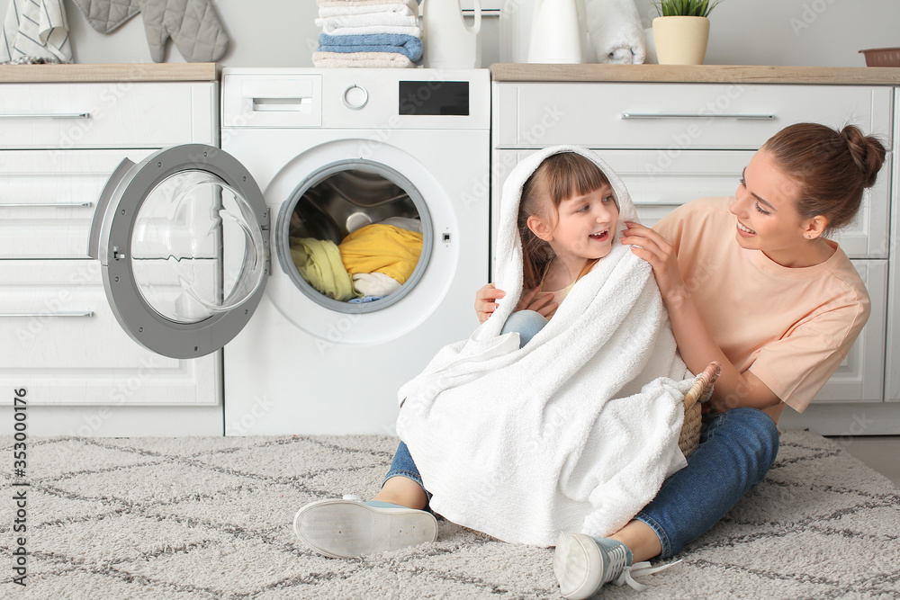 Woman and her cute little daughter doing laundry at home Woman and her cute little daughter doing laundry at home