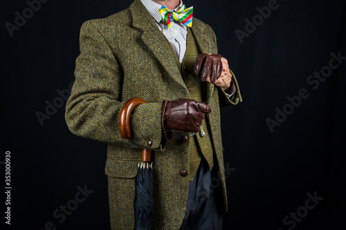 Portrait of Elegant Man in Vintage Tweed Suit With Umbrella Hanging Jauntily on Arm. Eccentric English Gentleman. Copy Space for Vintage Fashion. photo