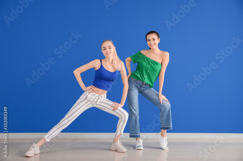 Beautiful young women dancing against color wall
