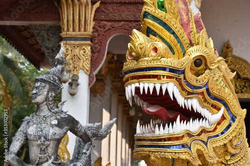 Golden Dragon Head in Foreground with Standing Statue in Background, Facing Left, Wat Chang Kham, Chiang Mai