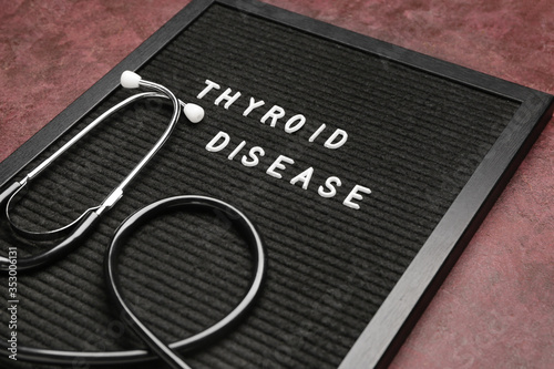 Board with text THYROID DISEASE and stethoscope on color background photo