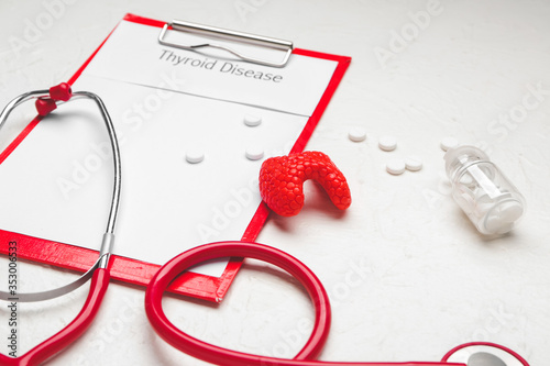 Clipboard with text THYROID DISEASE, pills and stethoscope on white background photo