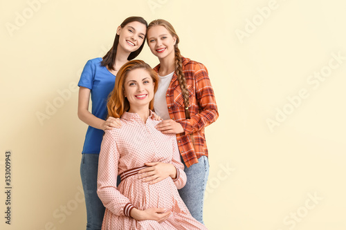 Lesbian couple and pregnant woman on color background. Surrogate motherhood concept © Pixel-Shot