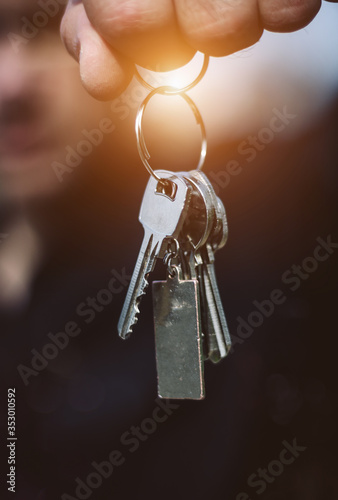 Real estate agent, house seller or realtor giving the new house keys. Man holding a bunch of apartment keys. Sale and moving concept, vertical image.
