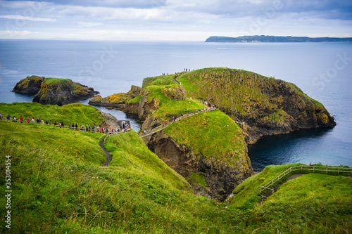 Carrick-a-Rede rope bridge in Northern Ireland with the lineup of tourists waiting to cross it. 