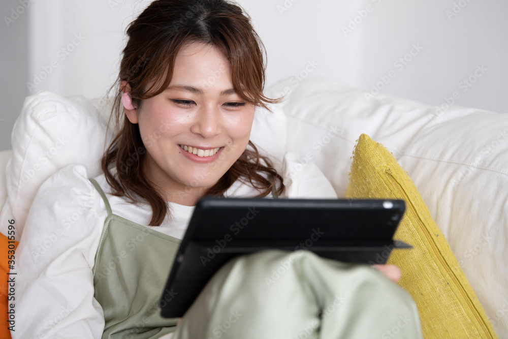 タブレット端末で動画配信を楽しむ女性
