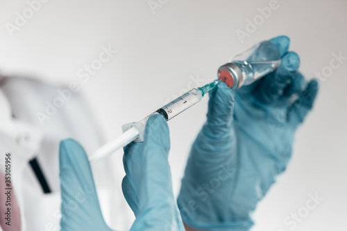Close-up image of hands with a syringe with vial.