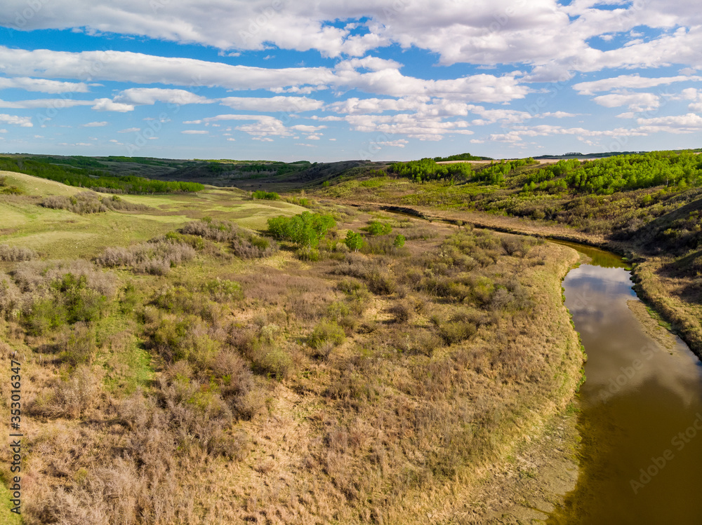 an aerial view of a peaceful stream flowing through the prairie province of Saskatchewan, Canada