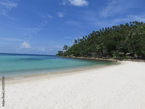 Fototapeta Naklejka Na Ścianę i Meble -  White sandy beach with Thailand with green palm trees and blue ocean in the background.