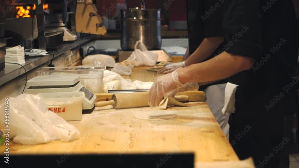 Someone's making dough on a wooden table. The chef is rolling out the dough in the restaurant kitchen. Hands wrinkle the dough. Food video close up kitchen. Someone's making dough on a wooden table. The chef is rolling out the dough in the restaurant kitchen. Hands wrinkle the dough. Food video close up kitchen.