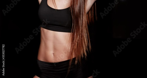 Close up girl shows sports stomach. Healthy fitness and eating lifestyle concept. Fitness sporty woman showing her well trained body, isolated over black background. 4K