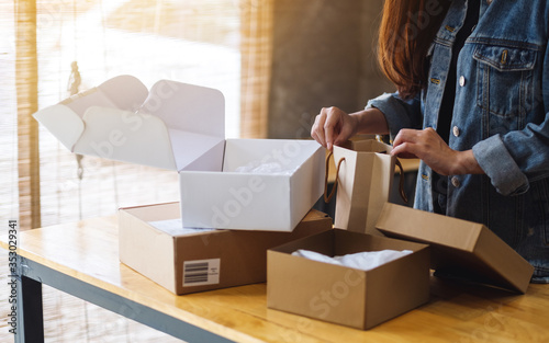 Closeup image of a woman opening and looking inside shopping bag at home for delivery and online shopping concept