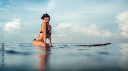 Photography Beautiful girl posing sitting on a surfboard in the ocean