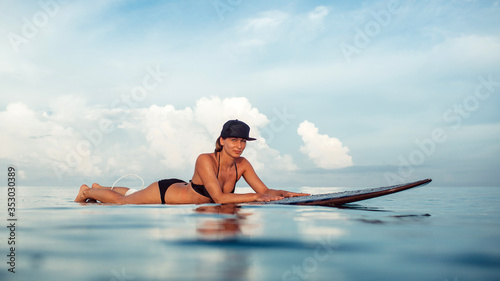 surfing on bali island, indonesia. photos from the water. Beautiful young girl and asian man ride on surf board