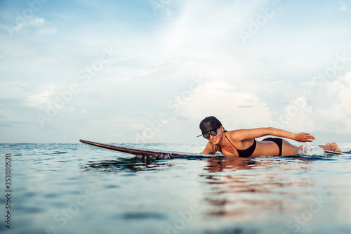 surfing on bali island, indonesia. photos from the water. Beautiful young girl and asian man ride on surf board