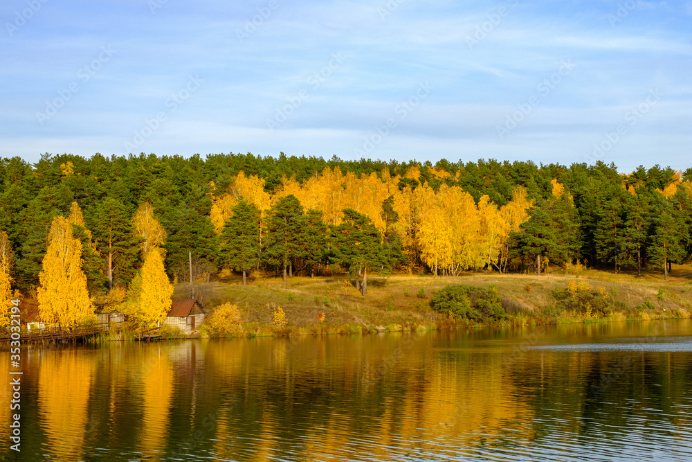 a large river in which the autumn mixed forest is reflected