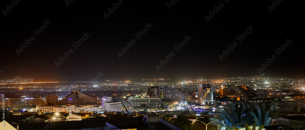 Night panoramic view on beach of the Red Sea in Eilat famous resort and recreation town in Israel and Aqaba cities - Jordan
