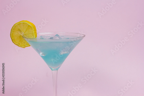 blue cocktail with lemon slice on a pink background