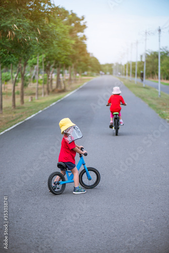 The boy wears a hat to prevent germs while he learns to ride a bike. It seems that he still has some concerns.