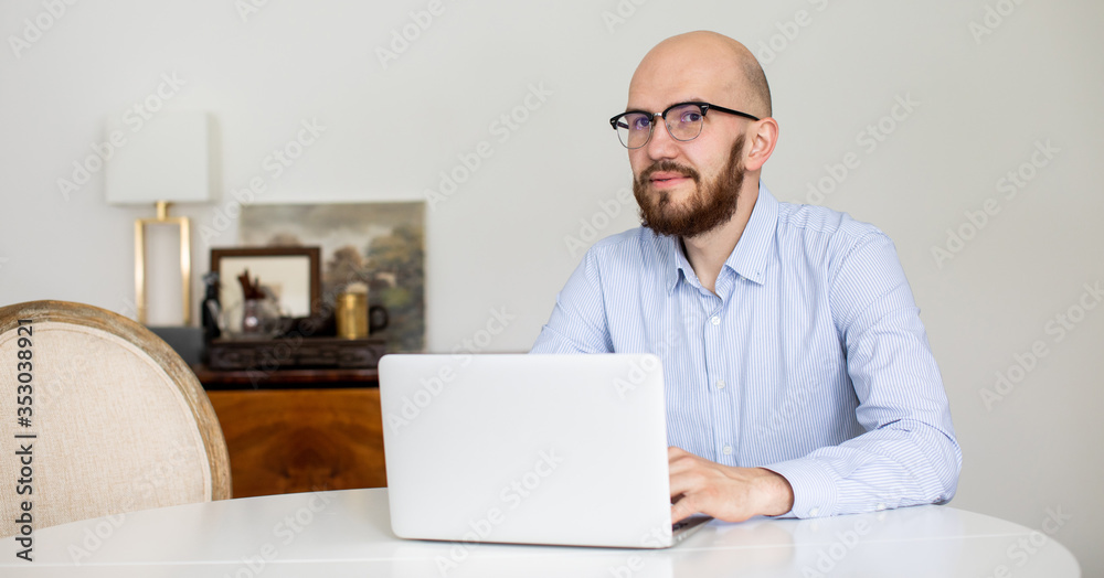 a man in a blue shirt with a beard is working on a laptop at home. Stay in home a man in a blue shirt with a beard is working on a laptop at home. Stay in home