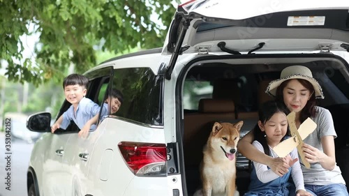Pet lover And Asian family. Mother and child are playing a paper plane on a car with a beautiful view. The boy waved Mother and child play plane in the back of the van.