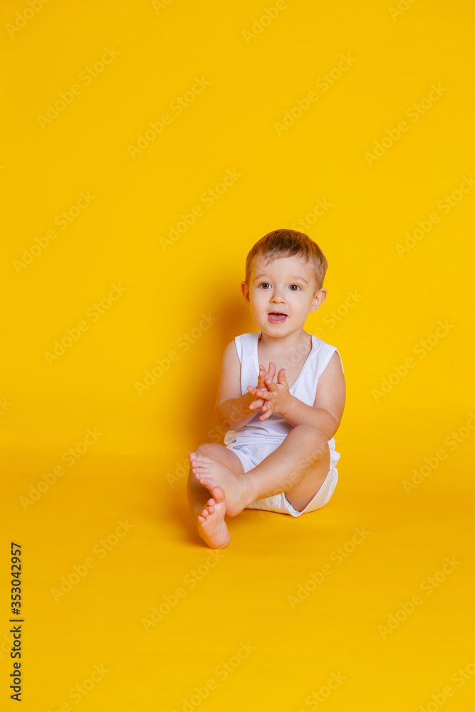 little boy in a t-shirt and underwear sitting on an orange-yellow background little boy in a t-shirt and underwear sitting on an orange-yellow background