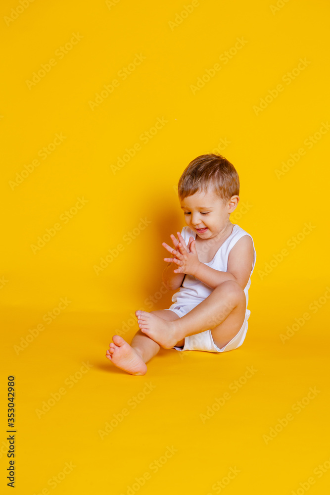 little boy in a t-shirt and underwear sitting on an orange-yellow background