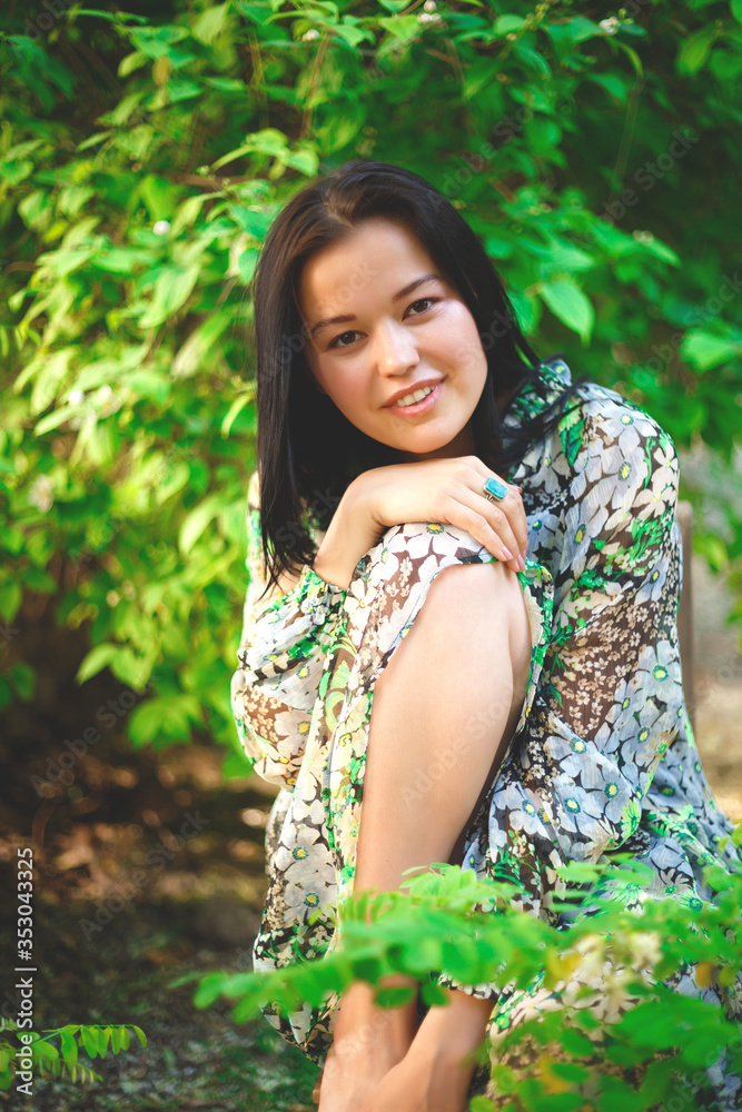 portrait of a beautiful smiling brunette on a background of greenery portrait of a beautiful smiling brunette on a background of greenery