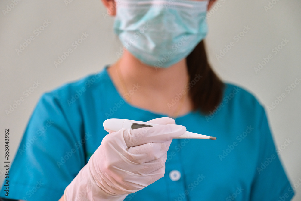 A female nurse with a digital thermometer in her hand A female nurse with a digital thermometer in her hand