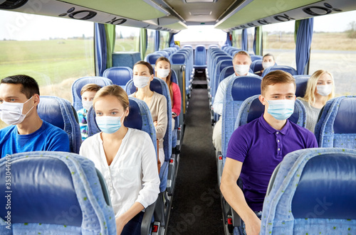 tourism, pandemic and health care concept - group of passengers or tourists wearing face protective medical mask for protection from virus disease in travel bus