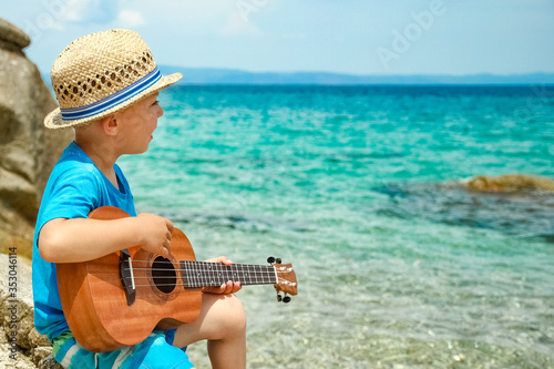 happy child playing guitar by the sea greece on nature background © Kostia