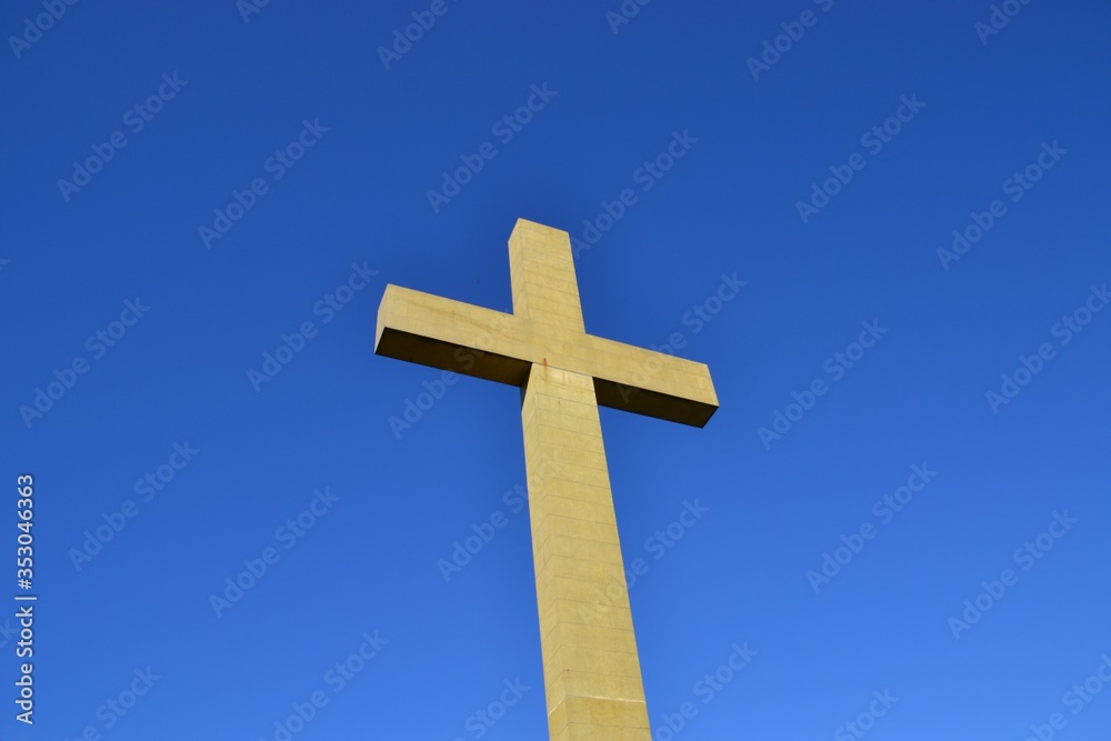 Low angle view of large concrete cross with blue sky