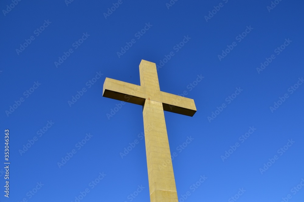 Low angle view of large concrete cross with blue sky Low angle view of large concrete cross with blue sky