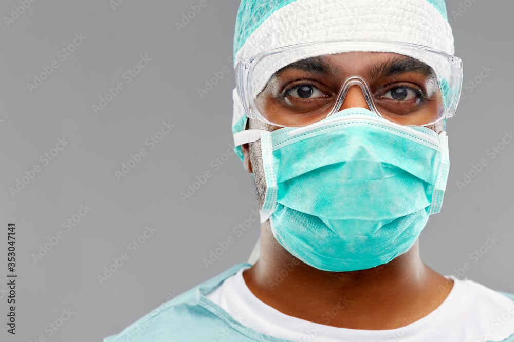 medicine, surgery and people concept - indian male doctor or surgeon in mask, goggles and protective wear over grey background medicine, surgery and people concept - indian male doctor or surgeon in mask, goggles and protective wear over grey background