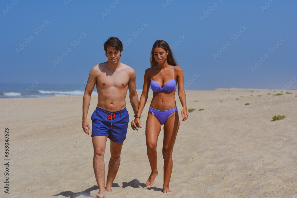 Beach couple walking on romantic travel vacation summer holidays romance. Young happy lovers, Latin woman and Caucasian man holding hands embracing outdoors. Beach couple walking on romantic travel vacation summer holidays romance. Young happy lovers, Latin woman and Caucasian man holding hands embracing outdoors.