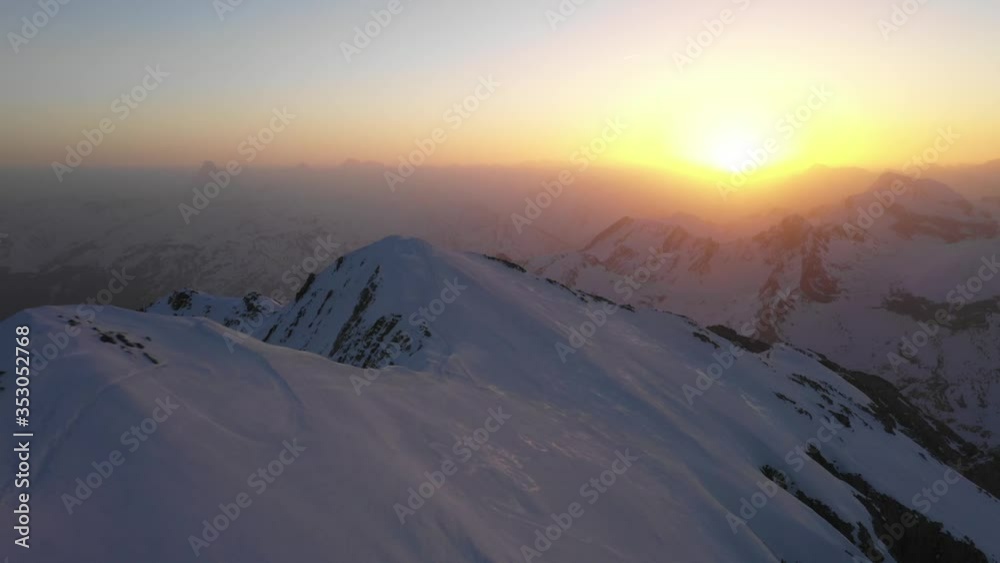 Glorious Sunset Over The Snowy Mountains In Pyrenees, Spain, Europe. Mountaineer Walking On The Top Of A Snowy Mountain.- aerial drone Glorious Sunset Over The Snowy Mountains In Pyrenees, Spain, Europe. Mountaineer Walking On The Top Of A Snowy Mountain.- aerial drone