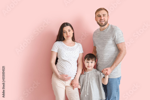 Beautiful pregnant woman with her family on color background © Pixel-Shot