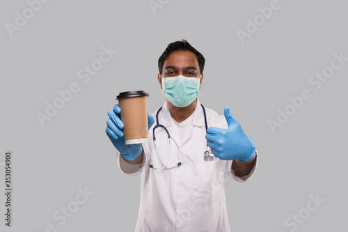 Indian Man Doctor Holding Coffee Take Away Cup Wearing Medical Mask and Gloves Showing Thumb Up Isolated. Indian Doctor Holding Coffee To Go Cup.