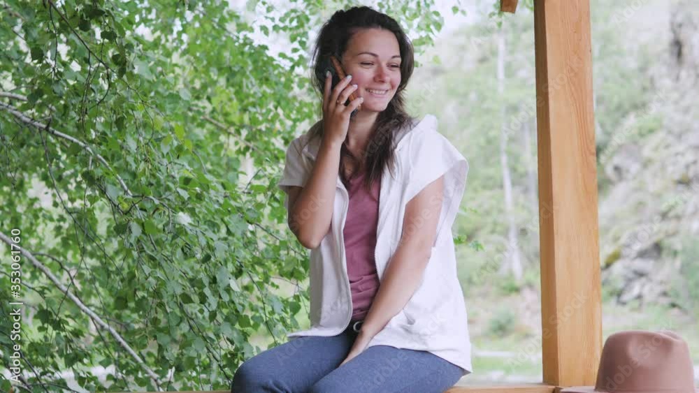 Attractive brunette in a hat and a white shirt with peas talking on a cell phone, taking a selfie on the phone, enjoying nature. Attractive brunette in a hat and a white shirt with peas talking on a cell phone, taking a selfie on the phone, enjoying nature.