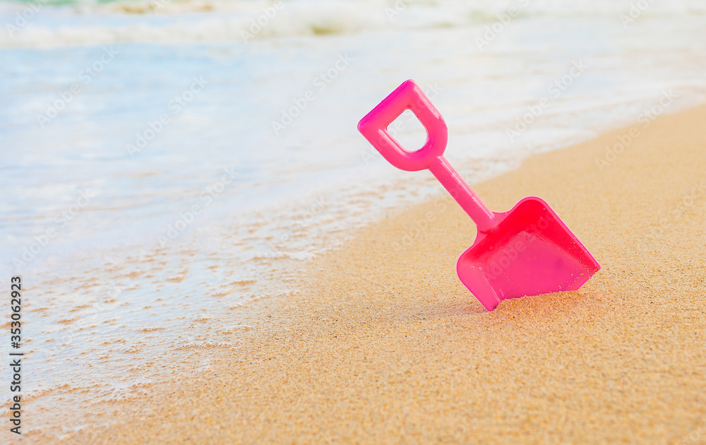 Closeup of colorful summer beach toy planted in the sand by the water. Family holiday concept. Closeup of colorful summer beach toy planted in the sand by the water. Family holiday concept.
