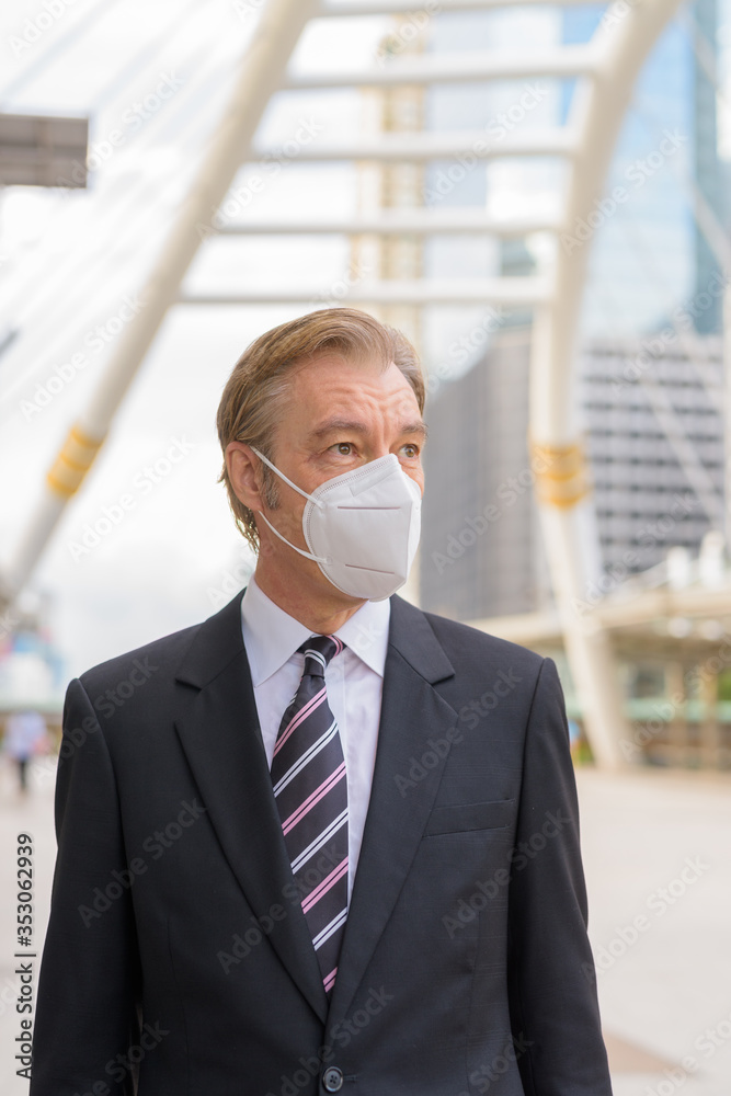 Mature businessman thinking with mask for protection from corona virus outbreak at skywalk bridge Mature businessman thinking with mask for protection from corona virus outbreak at skywalk bridge
