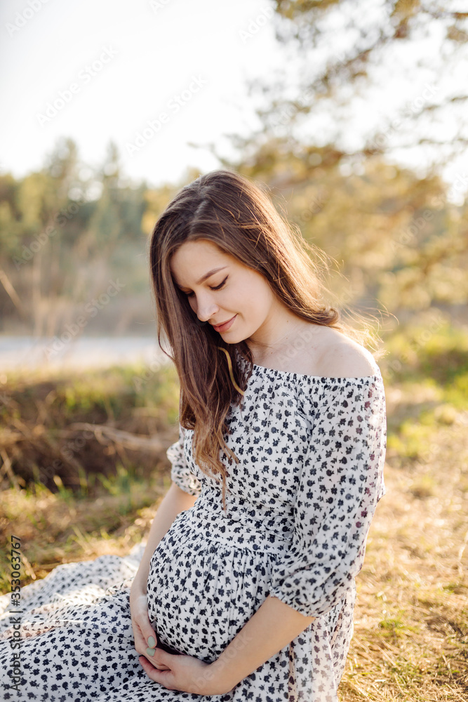 Young pregnant woman relaxing in park outdoors