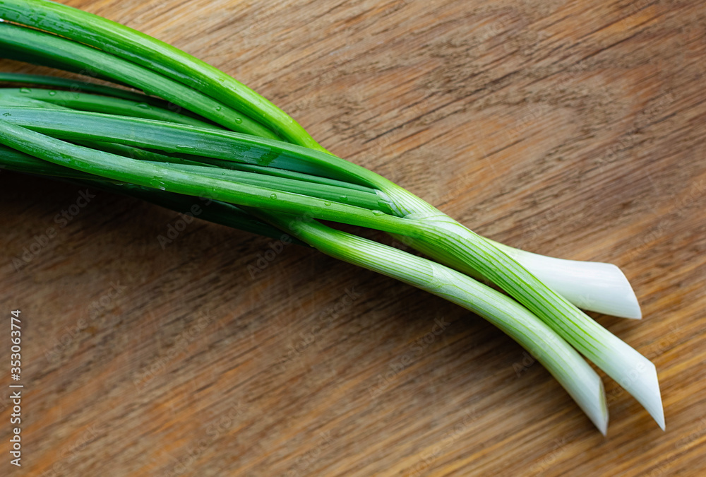 Young green onions on a wooden background. Fresh onion. Young green onions on a wooden background. Fresh onion.