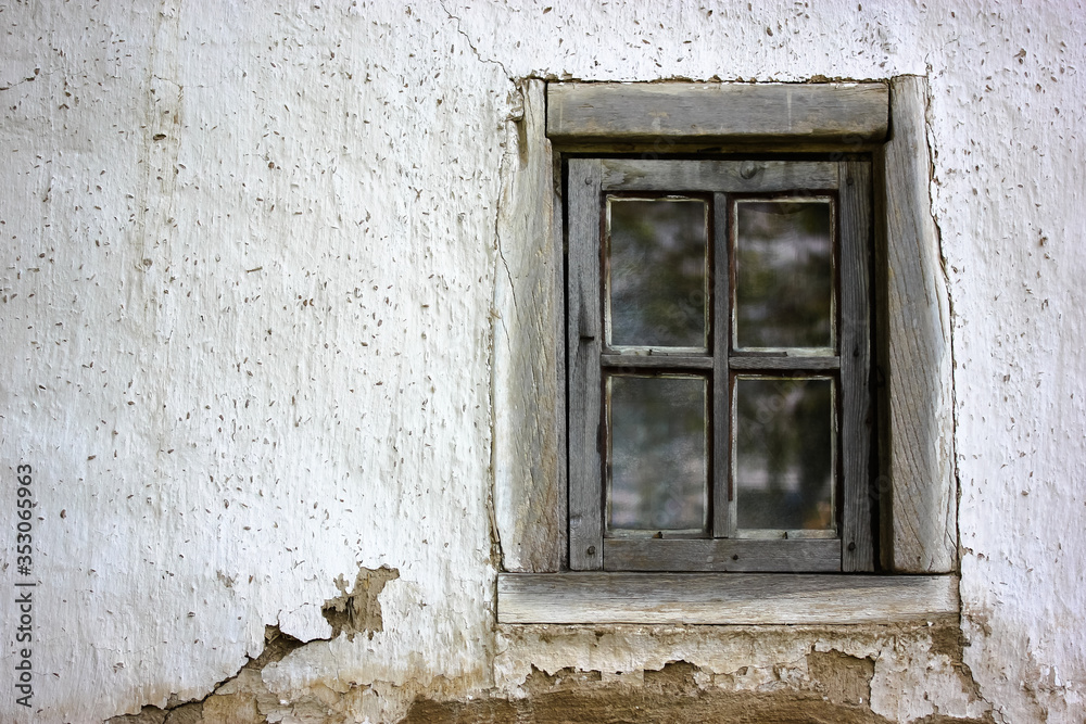 An old cracked window frame in a white house in the village
