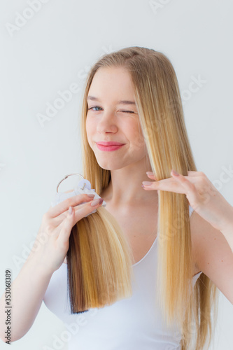 Stock Photo - Shot of 
young blonde girl combing her hair. Photo for a beauty salon. Hair treatments