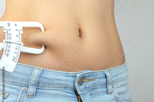 Obraz na plátně Body fat calipers, woman measuring subcutaneous percentage of fat on her belly